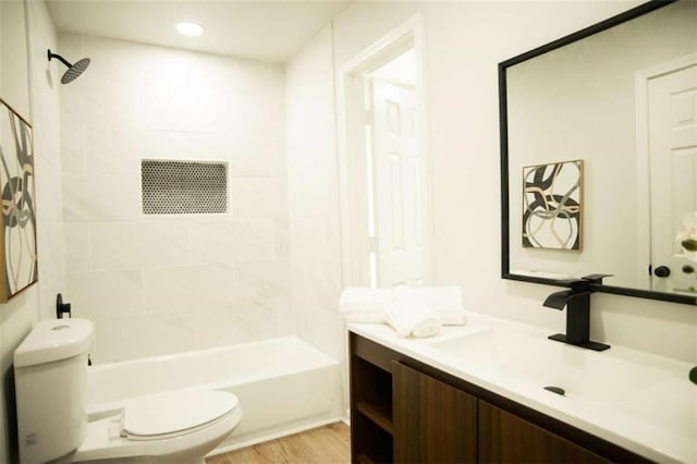 full bathroom with hardwood / wood-style floors, toilet, vanity, and tiled shower / bath combo