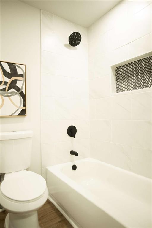 bathroom featuring toilet, tiled shower / bath combo, and hardwood / wood-style flooring