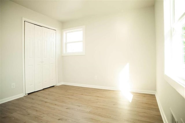 unfurnished bedroom featuring light wood-type flooring and a closet