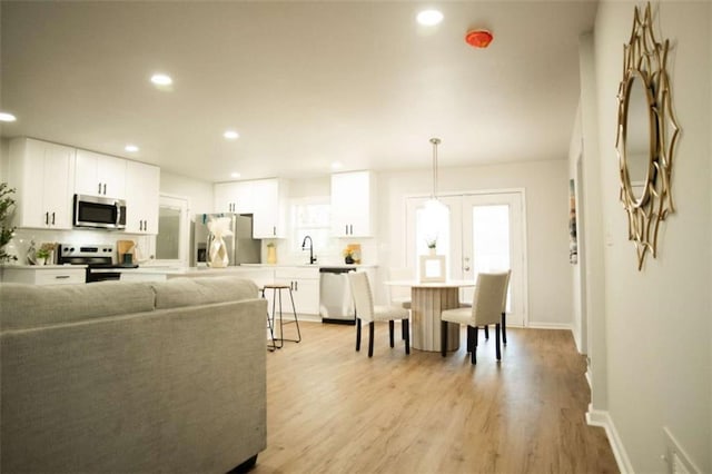 living room featuring light hardwood / wood-style floors, french doors, and sink