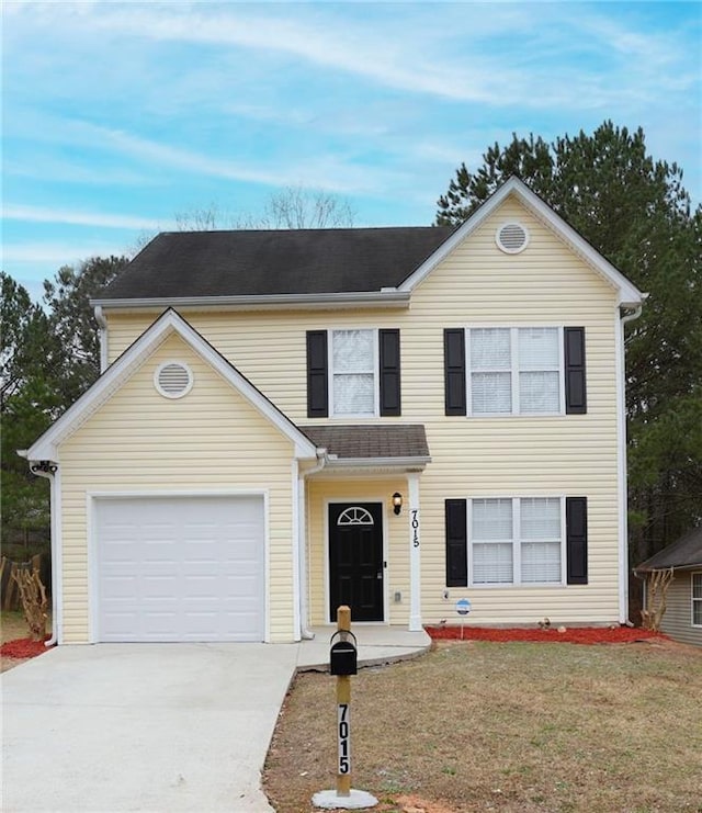 traditional-style home with concrete driveway, an attached garage, and a front yard