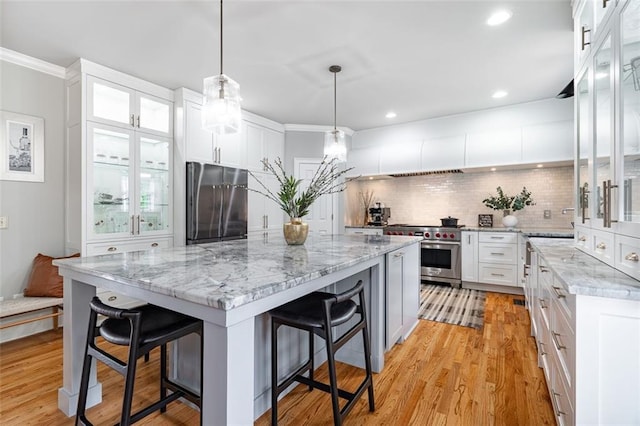 kitchen with appliances with stainless steel finishes, a breakfast bar area, a center island, white cabinetry, and decorative backsplash