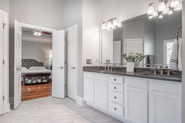 bathroom featuring a ceiling fan, double vanity, ensuite bath, and baseboards