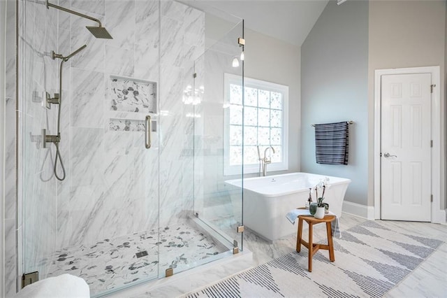 bathroom featuring vaulted ceiling, a marble finish shower, a freestanding bath, and baseboards