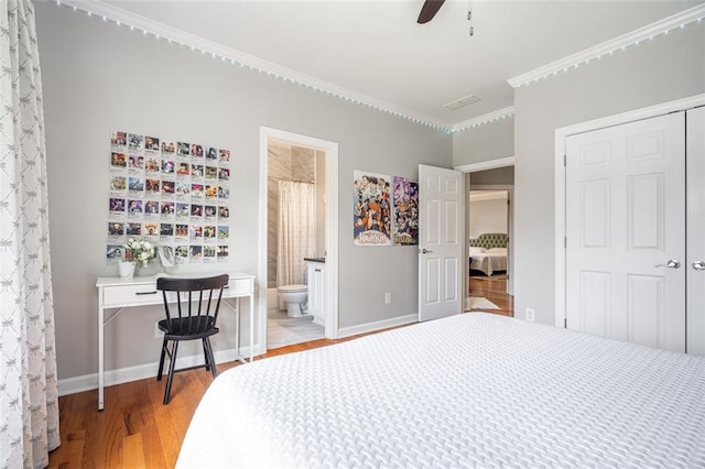 bedroom featuring light wood finished floors, a closet, baseboards, ornamental molding, and connected bathroom