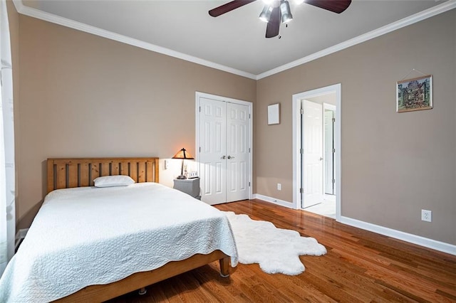 bedroom featuring baseboards, crown molding, wood finished floors, a closet, and ceiling fan