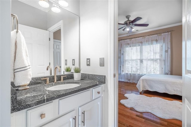 ensuite bathroom with vanity, a ceiling fan, wood finished floors, and ornamental molding