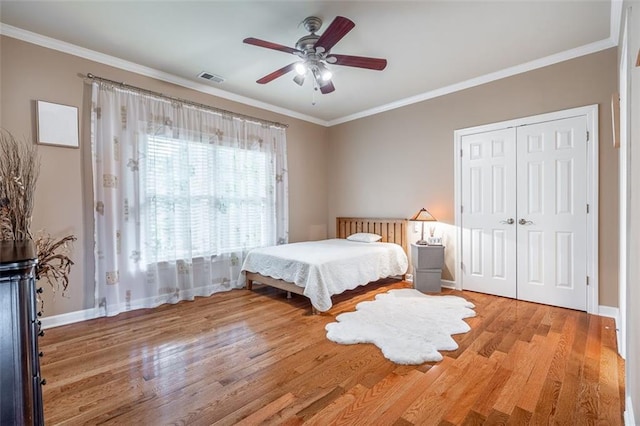 bedroom featuring wood finished floors, baseboards, ornamental molding, a closet, and a ceiling fan
