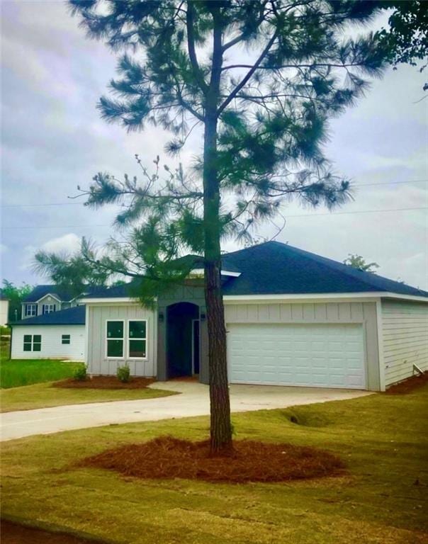 view of front of property with board and batten siding, a garage, driveway, and a front lawn