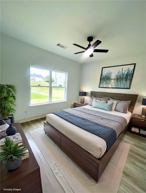bedroom featuring baseboards, ceiling fan, visible vents, and wood finished floors