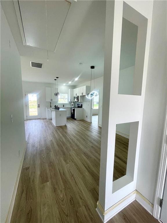 unfurnished living room featuring baseboards, attic access, and wood finished floors