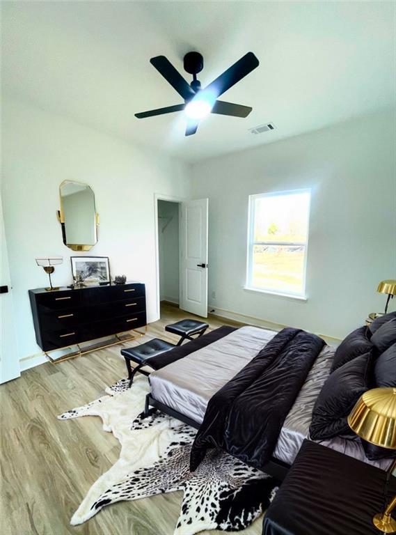 bedroom featuring ceiling fan, light wood finished floors, and visible vents