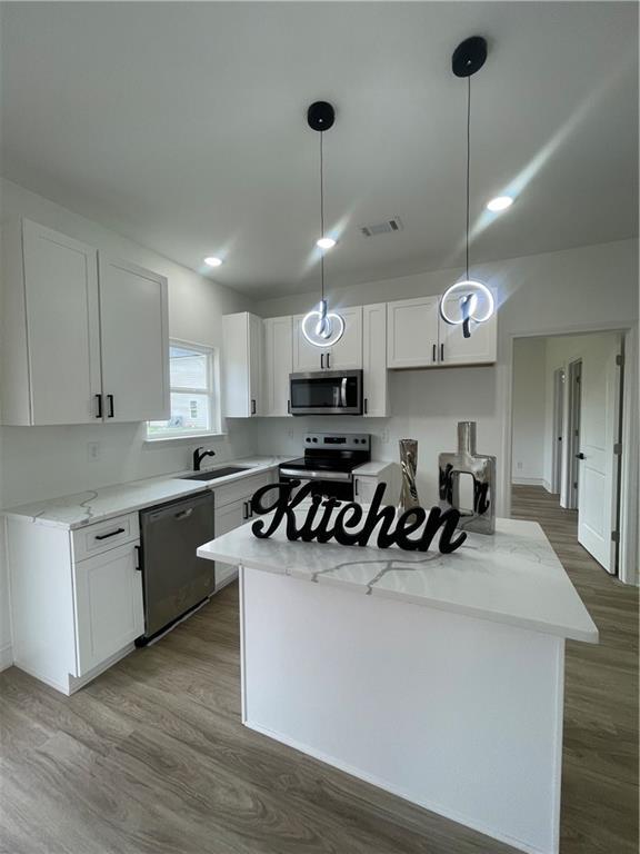 kitchen with a center island, a sink, wood finished floors, and stainless steel appliances