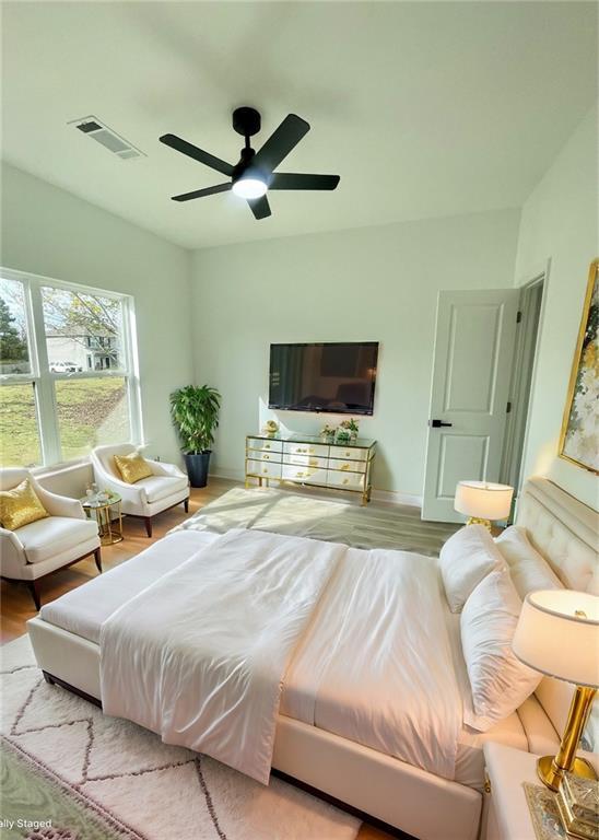 bedroom with baseboards, ceiling fan, wood finished floors, and visible vents
