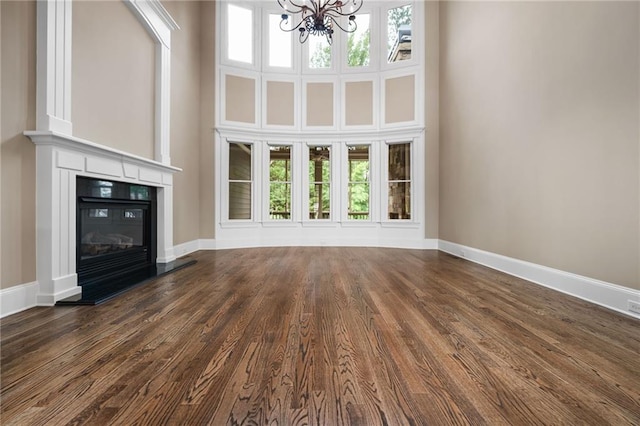 771 Tate Overlook, Marietta, GA 30064 - unfurnished living room featuring a chandelier, baseboards, a high ceiling, dark wood-style flooring, and a glass covered fireplace