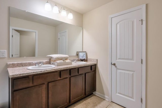 full bathroom with double vanity, baseboards, and a sink