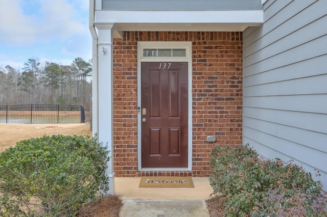 entrance to property with brick siding and fence