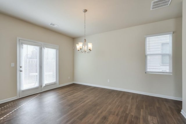 spare room with dark wood-style floors, visible vents, and baseboards