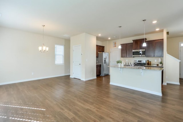 kitchen with open floor plan, hanging light fixtures, appliances with stainless steel finishes, and dark wood-style floors