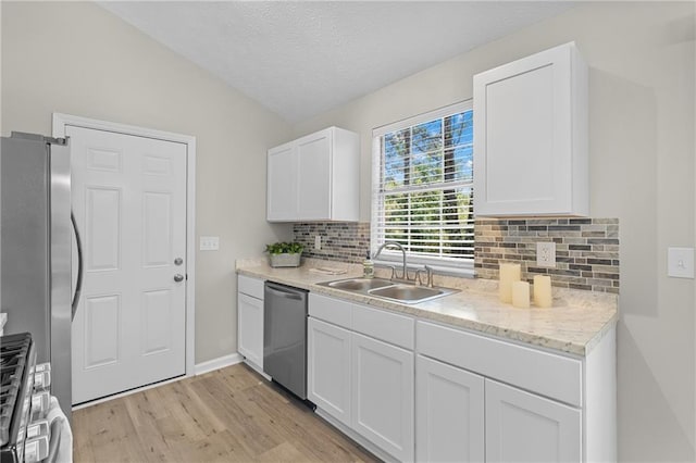 kitchen with backsplash, a sink, white cabinetry, light wood-type flooring, and stainless steel appliances