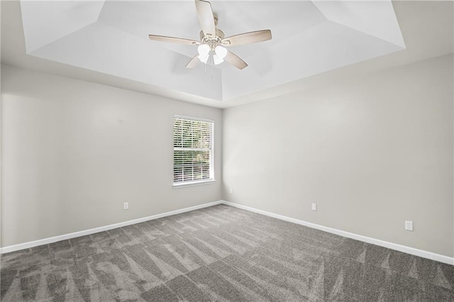 carpeted spare room featuring baseboards, a ceiling fan, and a raised ceiling