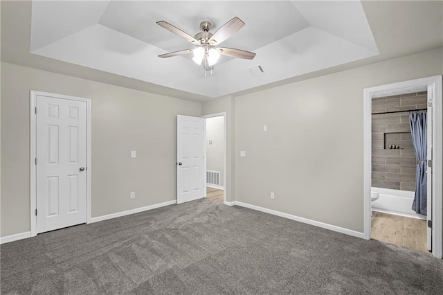 unfurnished bedroom featuring baseboards, carpet, and a raised ceiling