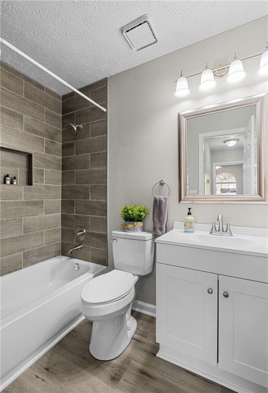 full bath featuring a textured ceiling, wood finished floors, toilet, and washtub / shower combination