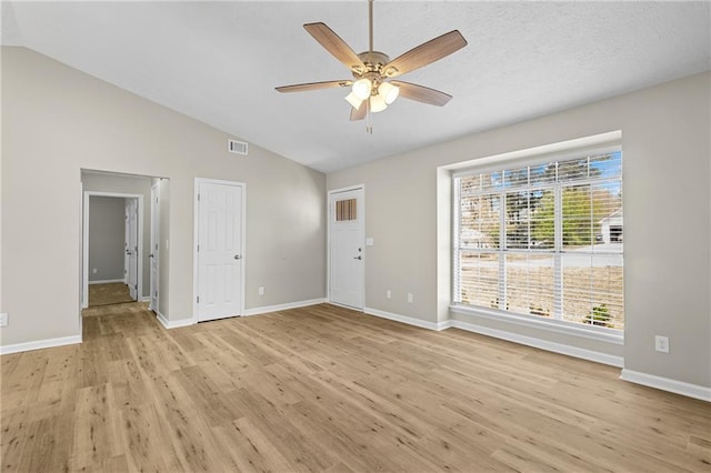 unfurnished living room featuring light wood finished floors, visible vents, lofted ceiling, and a ceiling fan