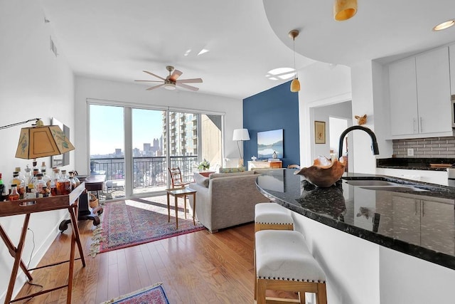 living room with ceiling fan, light hardwood / wood-style floors, and sink