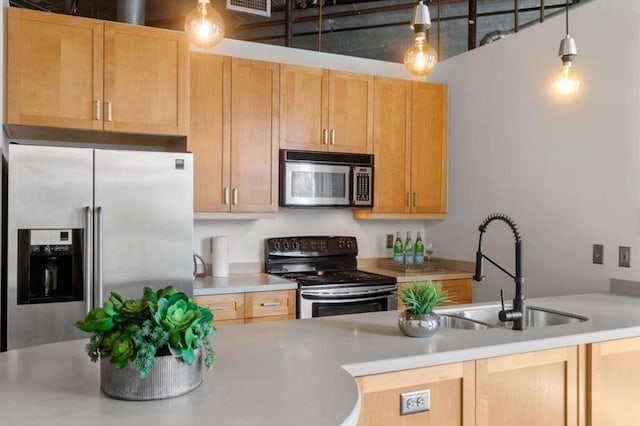 kitchen with light countertops, hanging light fixtures, appliances with stainless steel finishes, light brown cabinets, and a sink