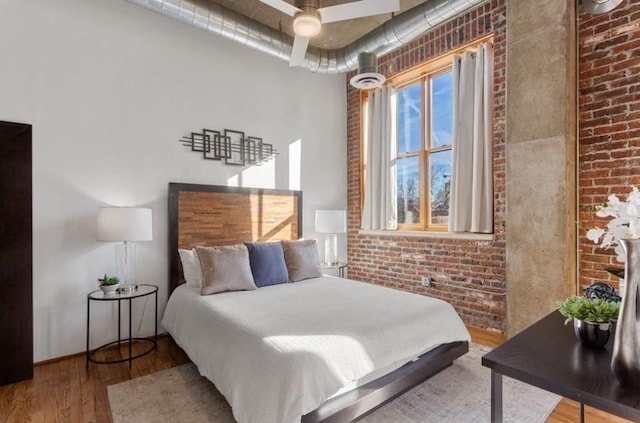 bedroom featuring brick wall and wood finished floors