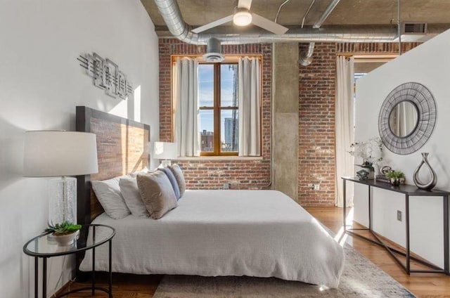 bedroom featuring brick wall, wood finished floors, and visible vents