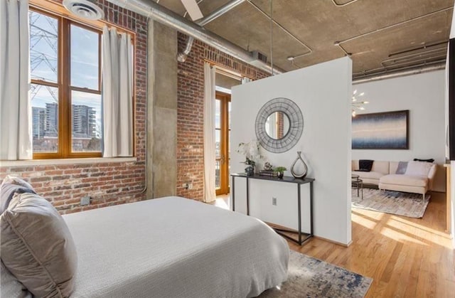 bedroom featuring brick wall and wood finished floors