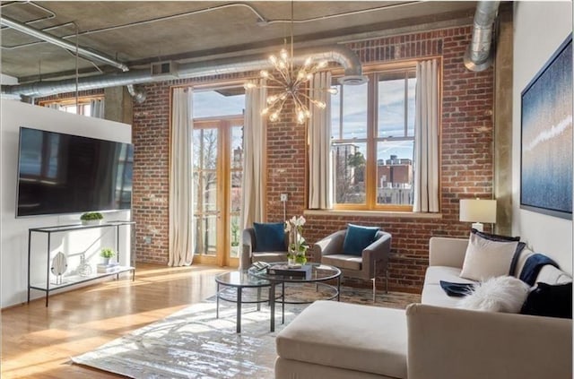 interior space featuring an inviting chandelier, brick wall, visible vents, and wood finished floors