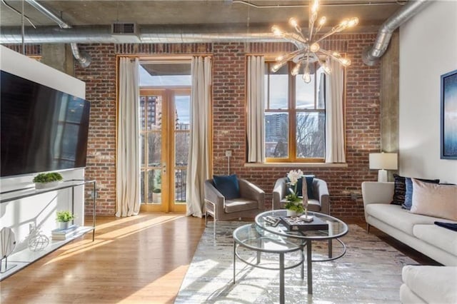 living room featuring visible vents, brick wall, and wood finished floors