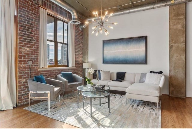 living area with an inviting chandelier, brick wall, and wood finished floors