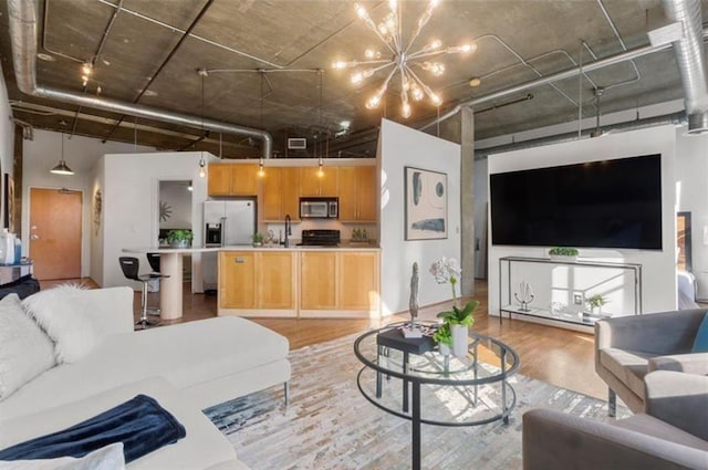 living room with light wood-style floors, a notable chandelier, and a high ceiling