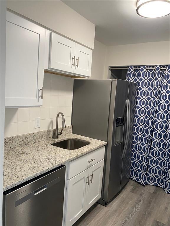 kitchen with appliances with stainless steel finishes, white cabinetry, and dark wood-type flooring