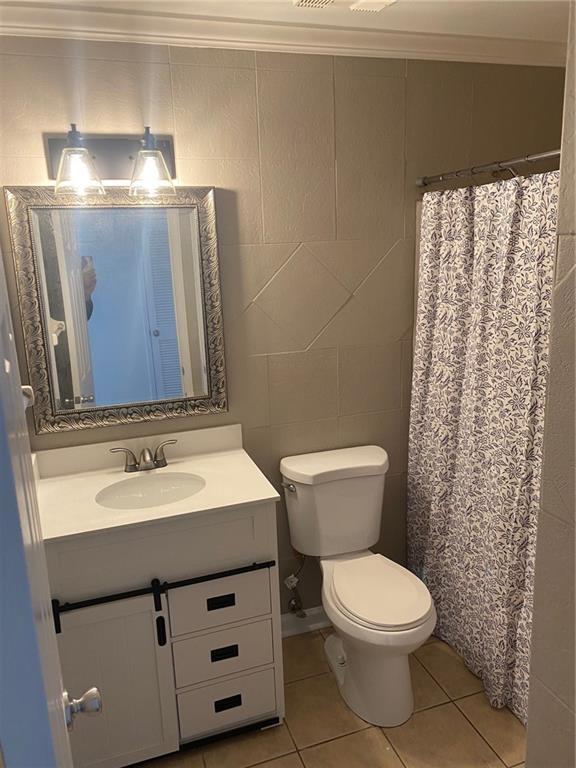 bathroom featuring vanity, tile patterned floors, tile walls, and crown molding