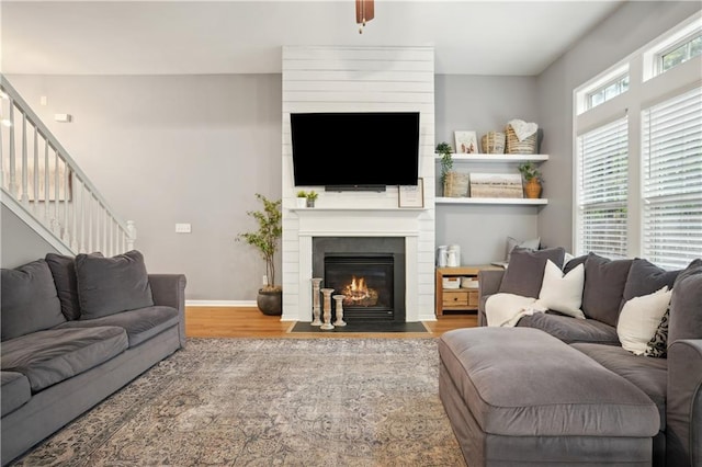 living area featuring plenty of natural light, a fireplace, baseboards, and wood finished floors