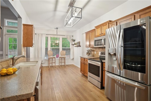 kitchen with tasteful backsplash, a sink, appliances with stainless steel finishes, a healthy amount of sunlight, and brown cabinetry