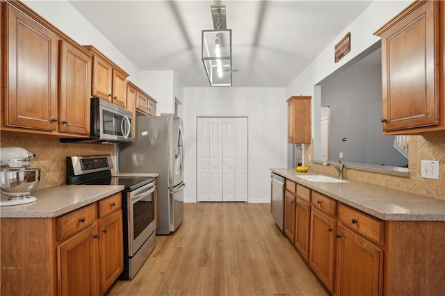 kitchen with brown cabinetry, decorative backsplash, a sink, and stainless steel appliances