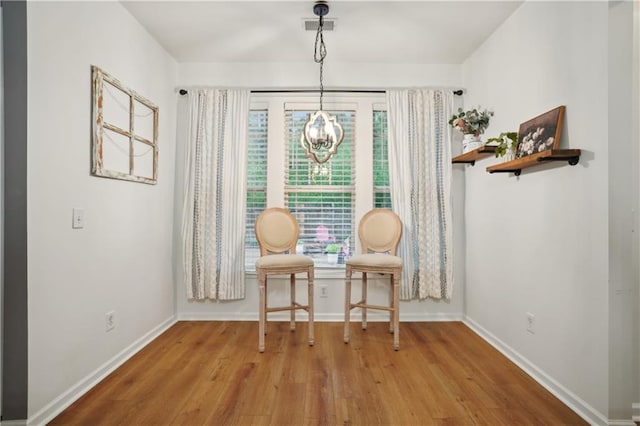 sitting room with a chandelier, visible vents, baseboards, and wood finished floors