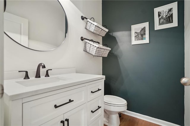 bathroom featuring toilet, wood finished floors, vanity, and baseboards