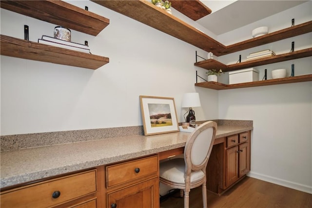home office featuring built in desk, wood finished floors, and baseboards