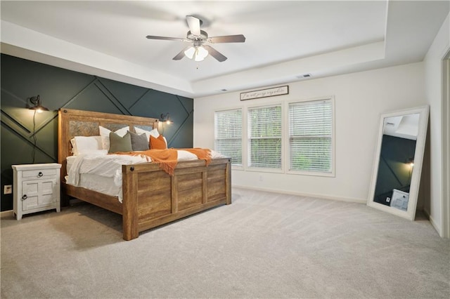 carpeted bedroom featuring visible vents, a tray ceiling, baseboards, and a ceiling fan