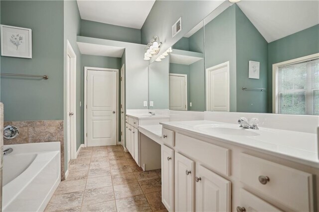 bathroom featuring a bath, double vanity, a sink, and visible vents