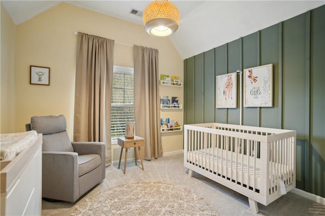 bedroom featuring visible vents, light colored carpet, a crib, and vaulted ceiling