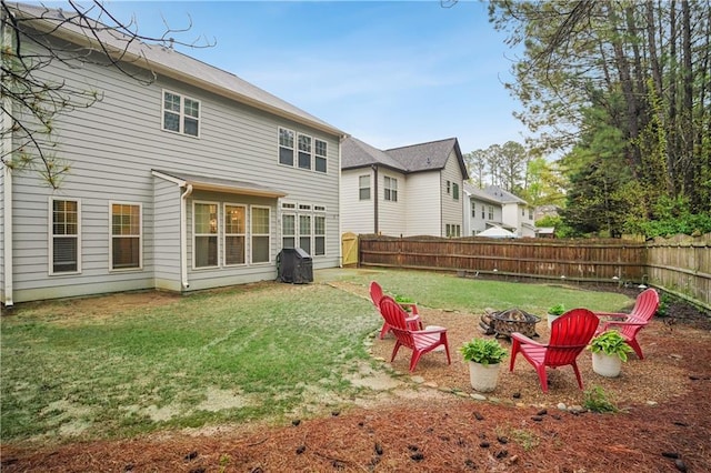 back of house featuring a yard, fence, and a fire pit
