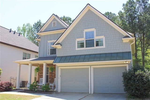 view of front facade with a standing seam roof, a porch, metal roof, an attached garage, and driveway
